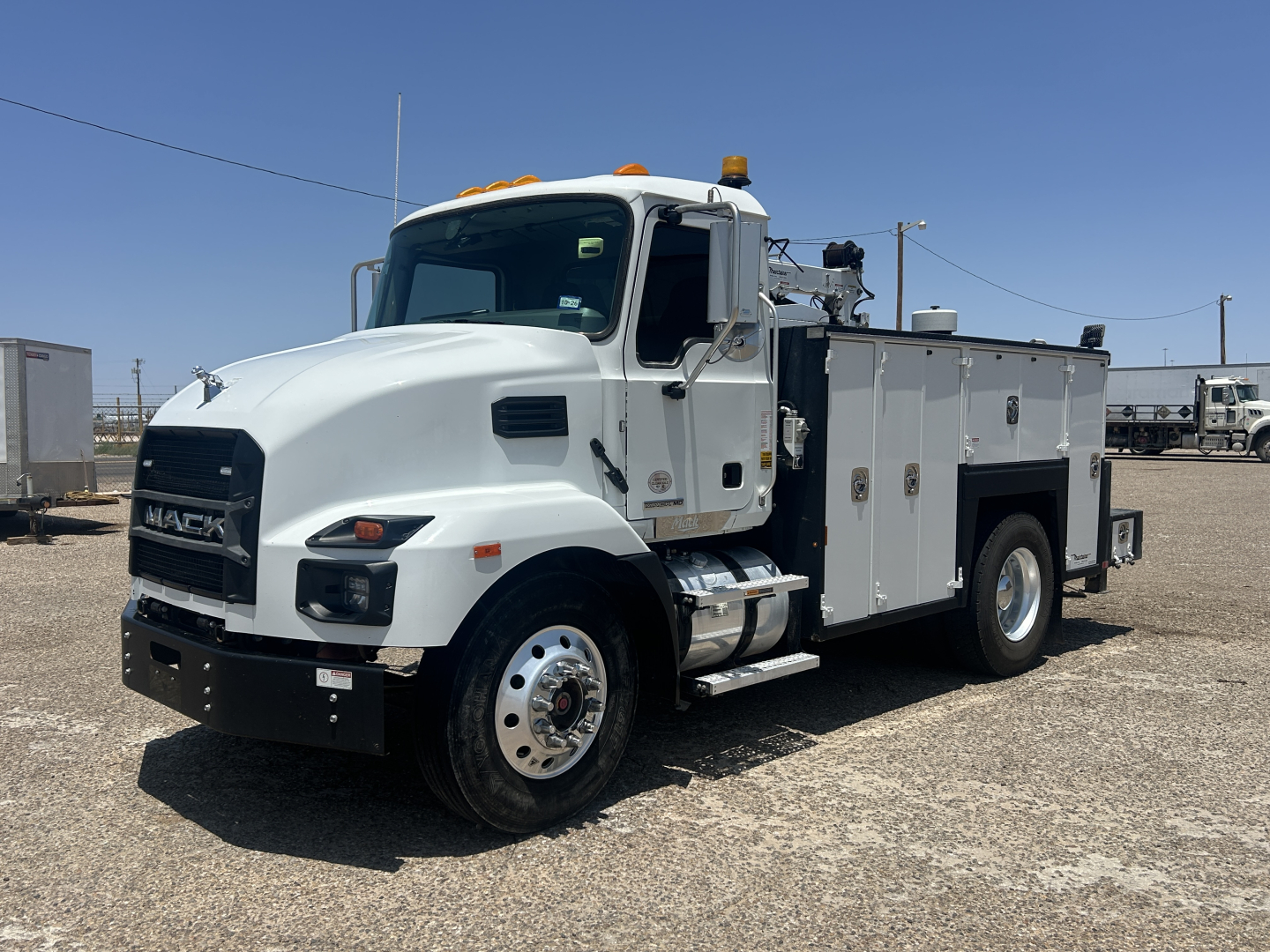 Mack MD642 service truck with utility compartments and orange beacon lights on cab; front grille shows MACK; side compartments along body with equipment doors.