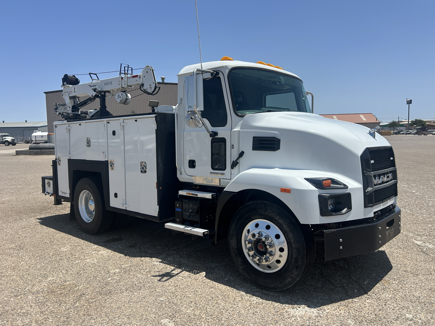 Mack MD642 service truck side view showing service bed with compartments and crane equipment on rear, white cab with black grille.