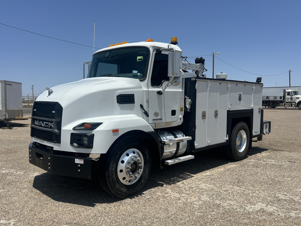 Mack MD642 service truck with utility compartments and orange beacon lights on cab; front grille shows MACK; side compartments along body with equipment doors.