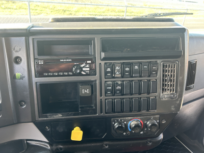 Dashboard center console of a Mack MD642 cab showing radio, switches, ignition area, and HVAC dials; yellow emergency fuel switch cap visible.