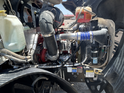 Mack MD642 engine bay showing coolant reservoir and intake piping, alternator, belts, and various hoses in-service view.