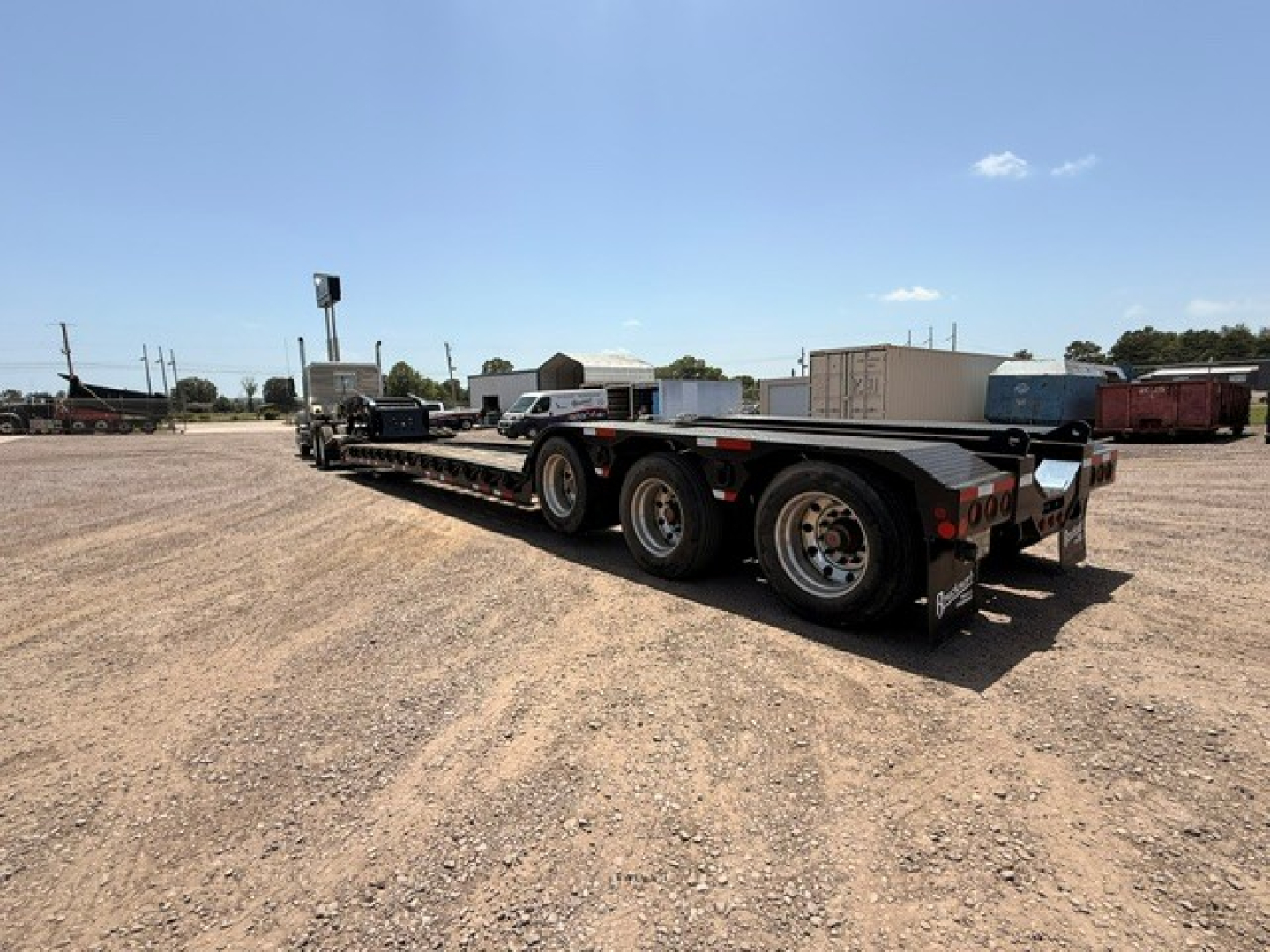  Fontaine MAG55H lowboy trailer showing triple-axle configuration and long flatbed design with storage boxes and rear group of wheels.