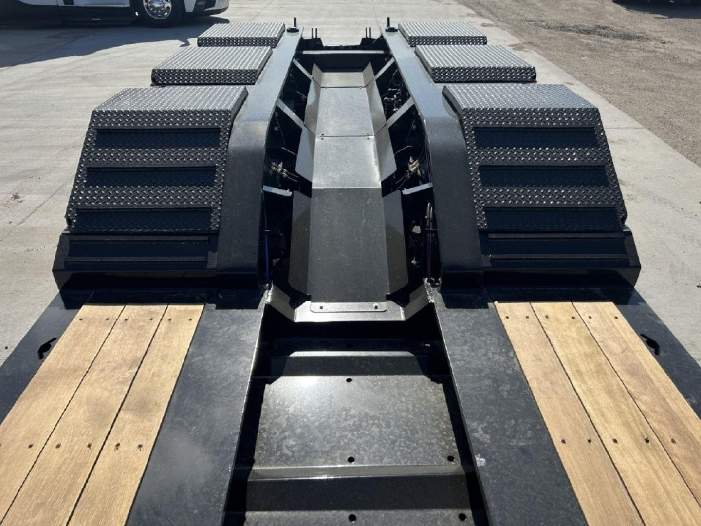 Trailer deck with heavy-duty LDH Lowboy spacers and wood-planked ramps showing rugged steel components and textured fenders.
