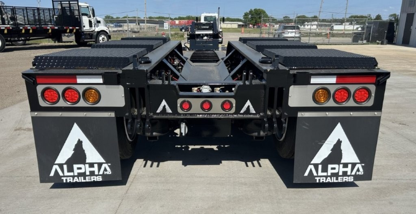Trailer rear view shows Alpha Trailers LDH lowboy with 26' deck, dual rear decks, taillights, mud flaps, and branding.