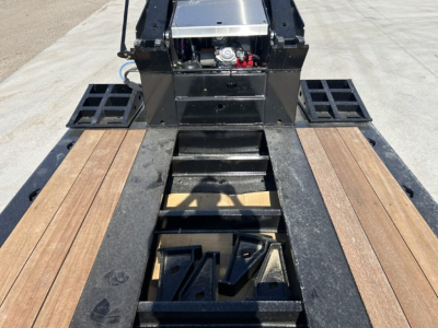 Trailer deck and gooseneck of 2027 Alpha A110HDG-SF-18 inch LDH lowboy showing wooden deck planks and hydraulic components.