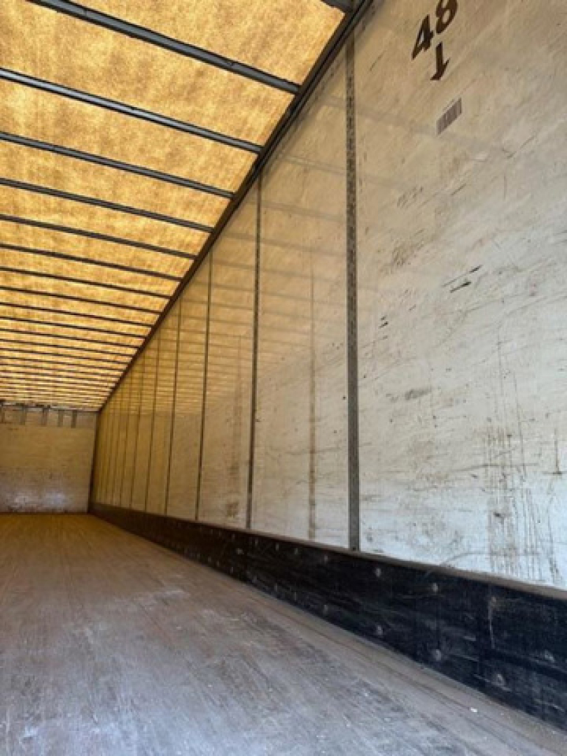 Trailer interior showing wooden floor and white side wall panels inside a Wabash van trailer.