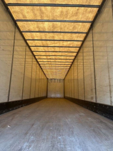Interior of a Wabash van trailer empty cargo area with wooden floor and metal walls, long rectangular perspective.