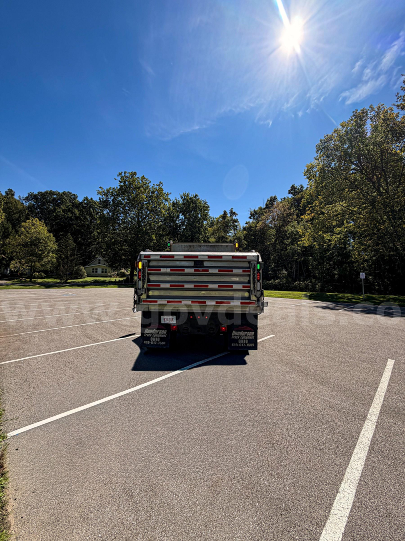 Dump truck rear showing plow-equipped International 7400 tailgate with reflective red/white bars.