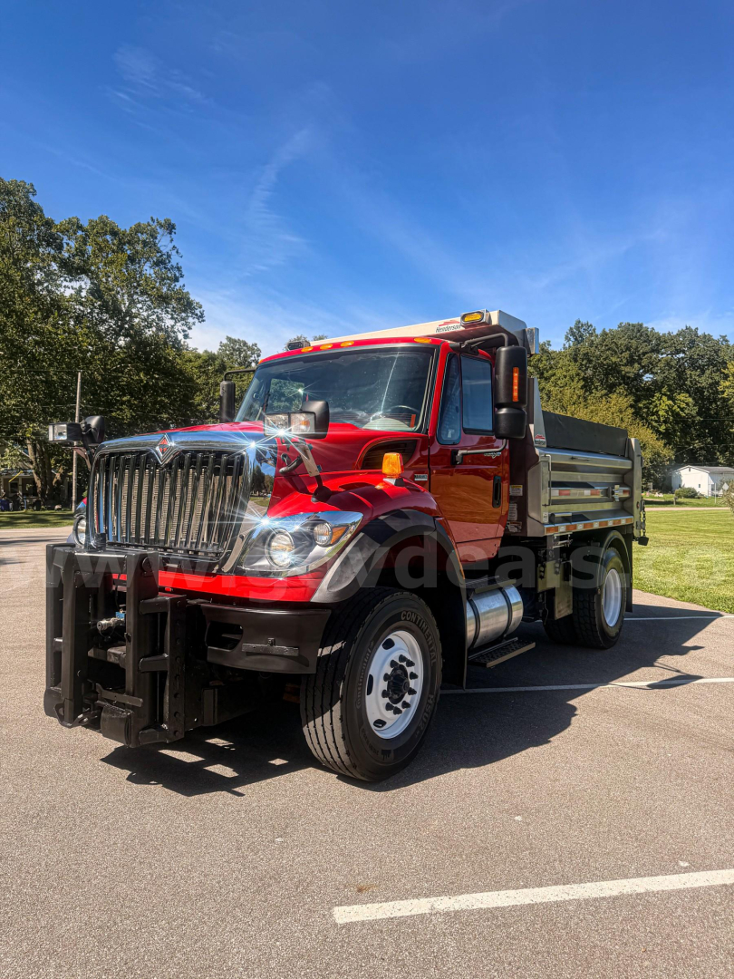 Red and orange International dump truck with plow equipment and chrome grille, showing front and passenger side.