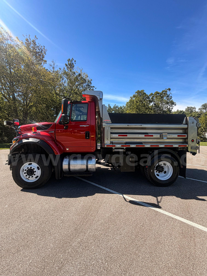 Truck cab and dump body side view showing red Internationals 7400 with silver dump box and chrome exhaust tank in daylight.