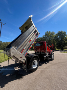 Truck bed tilted to dump with plow truck body showing dump bed and rear wheels.