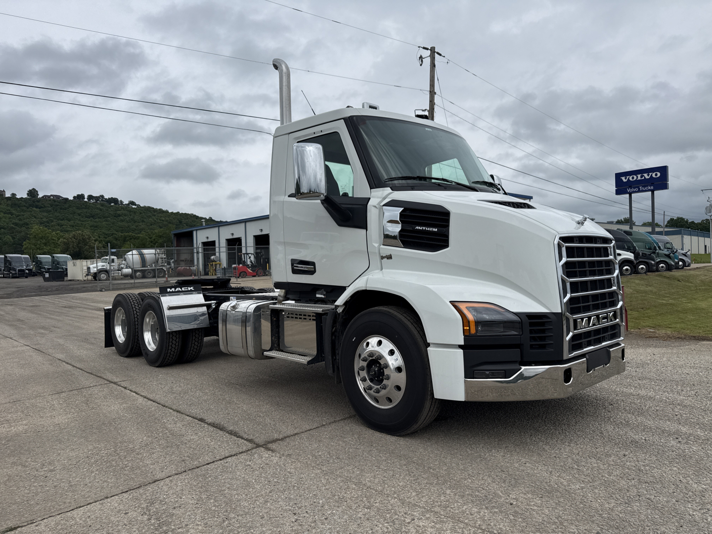 Truck: 2027 Mack AN64T conventional daycab with white exterior, front grille, dual exhaust, cab mirrors, and six-wheel configuration parked in a lot.