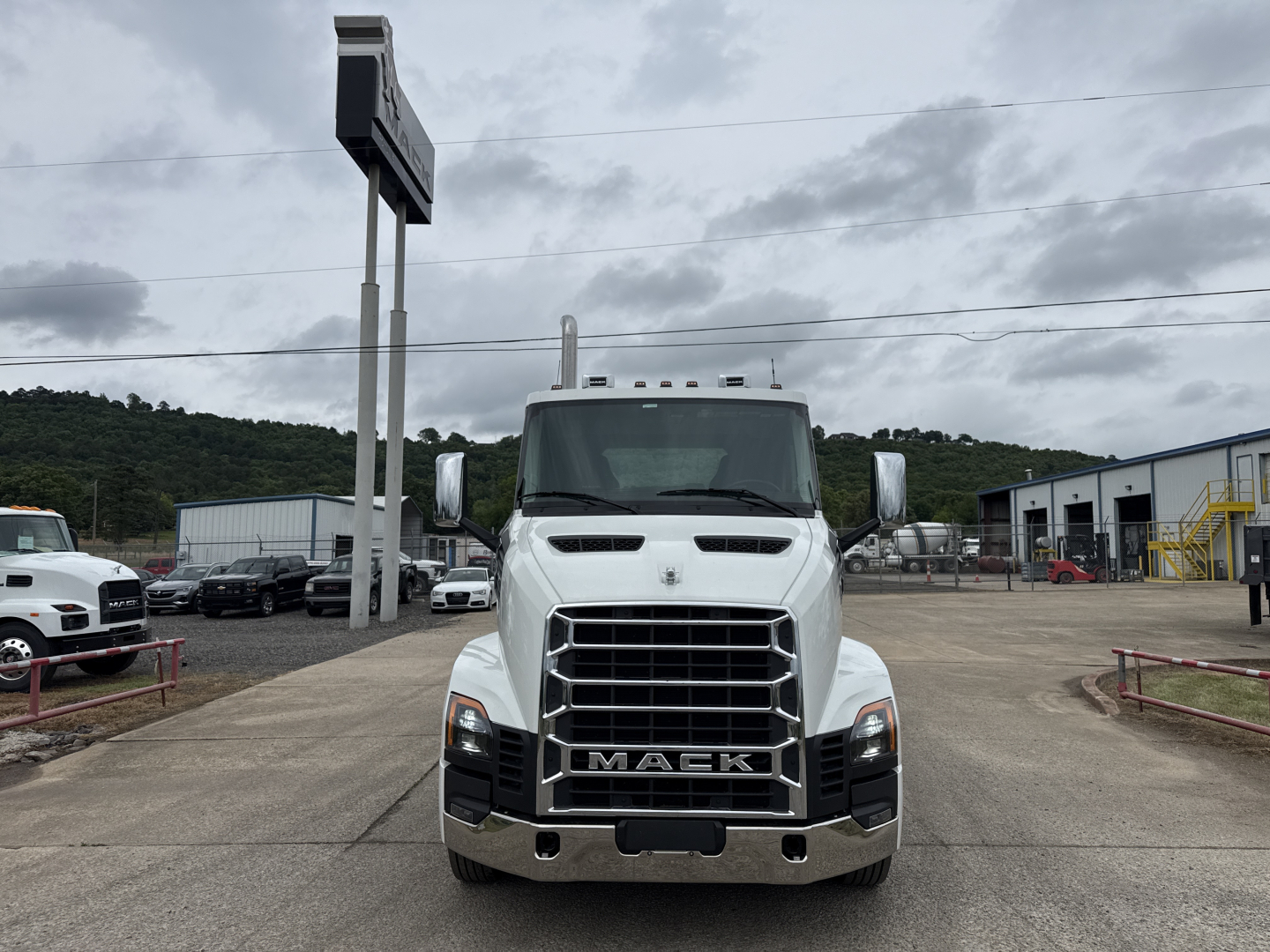 Mack AN64T conventional daycab truck front view in a dealership lot showing bold grille, chrome bumper, and Mack emblem.