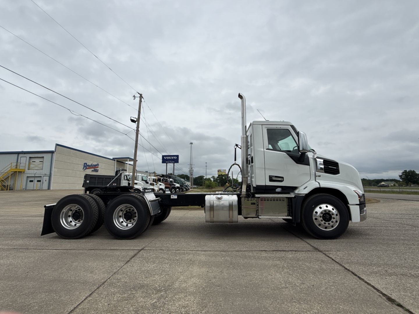 Mack AN64T conventional daycab truck side view showing tractor with white cab and dual rear axles, fuel tank, and exhaust stack.