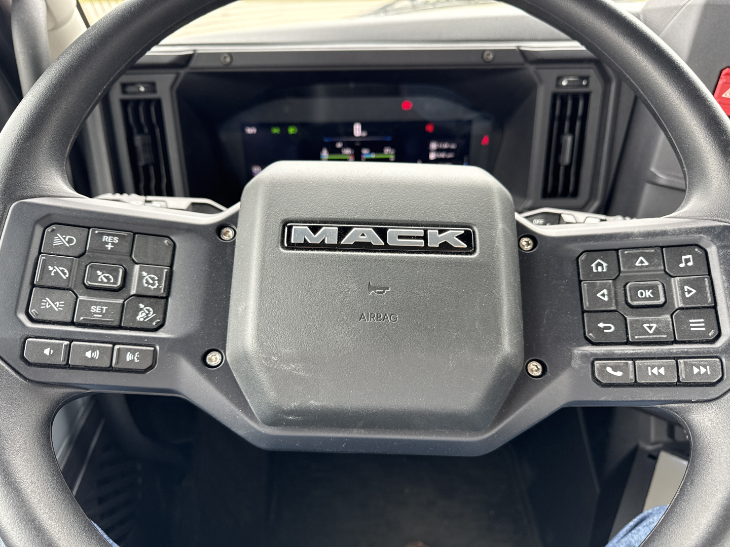 Mack AN64T steering wheel with Mack logo center, dashboard visible in background.