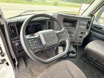Mack AN64T truck cab interior showing steering wheel, dashboard screens, and center console with controls.