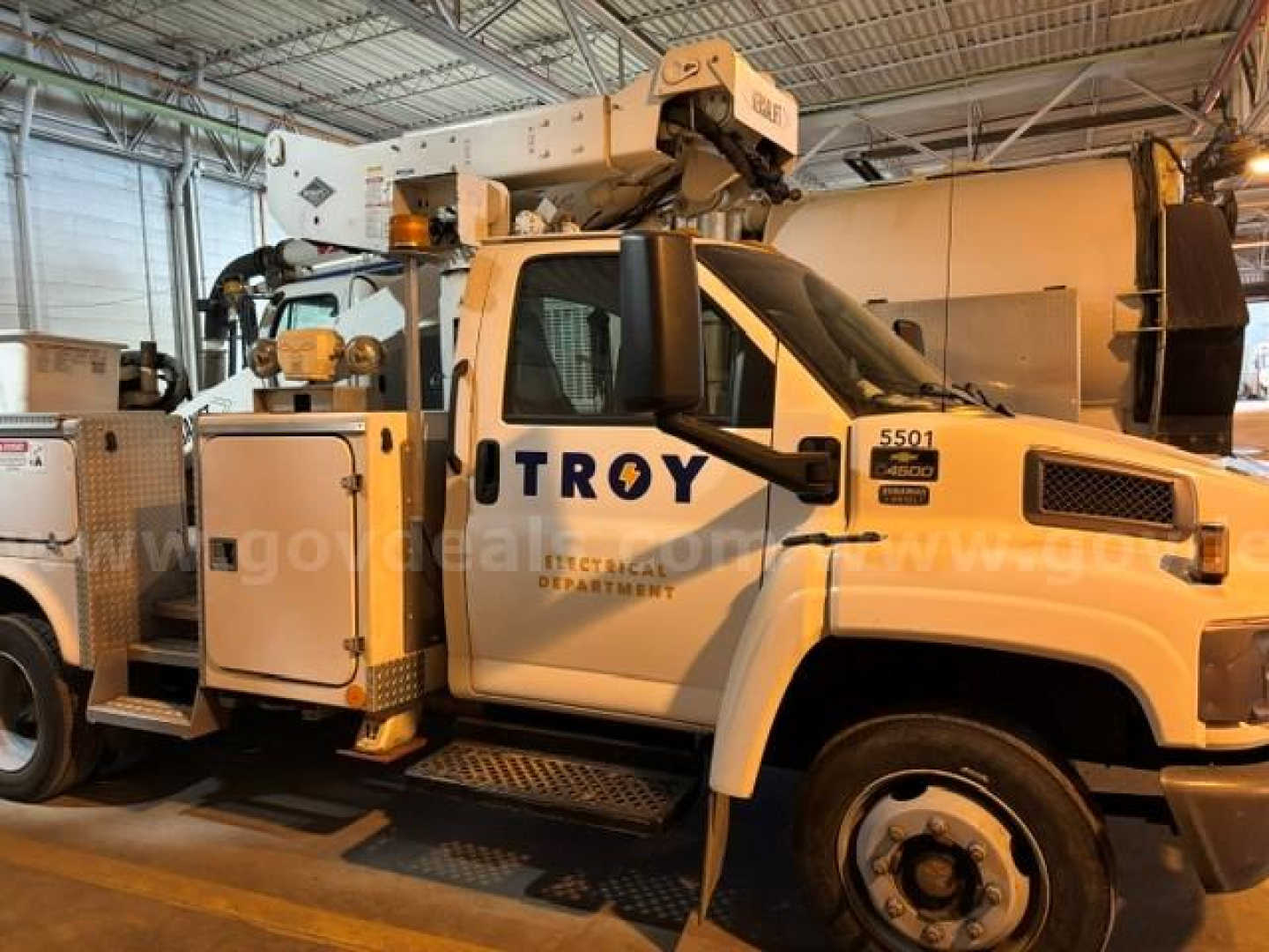 Truck equipment bay showing Troy Electrical Department bucket truck with mounted crane and utility compartments.