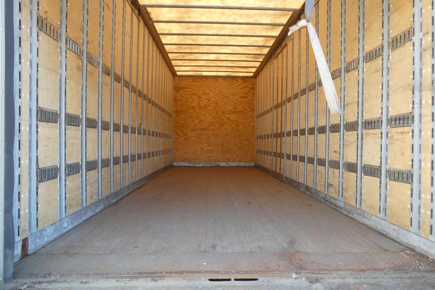 Interior of an empty truck box with wooden side walls and metal rails.