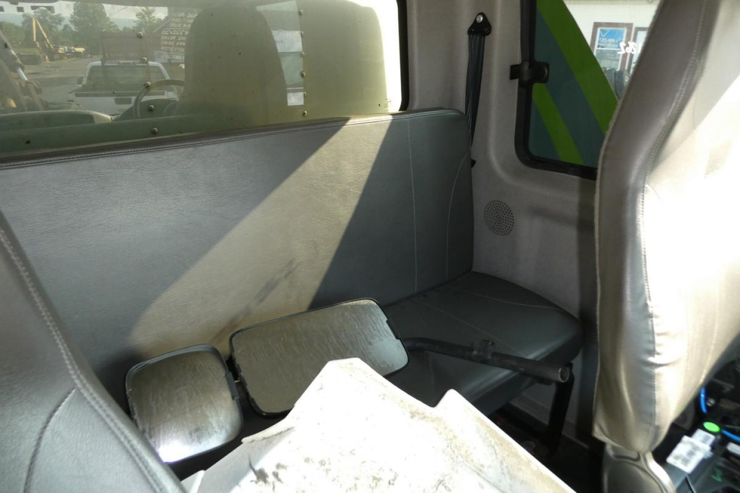 Truck cab interior showing back seat area with headrest and window; miscellaneous metal panels and cargo area visible.