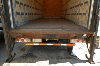 Truck bed of a 2017 International 4300 SBA from rear showing cargo area and bumper with lights and reflector strip.