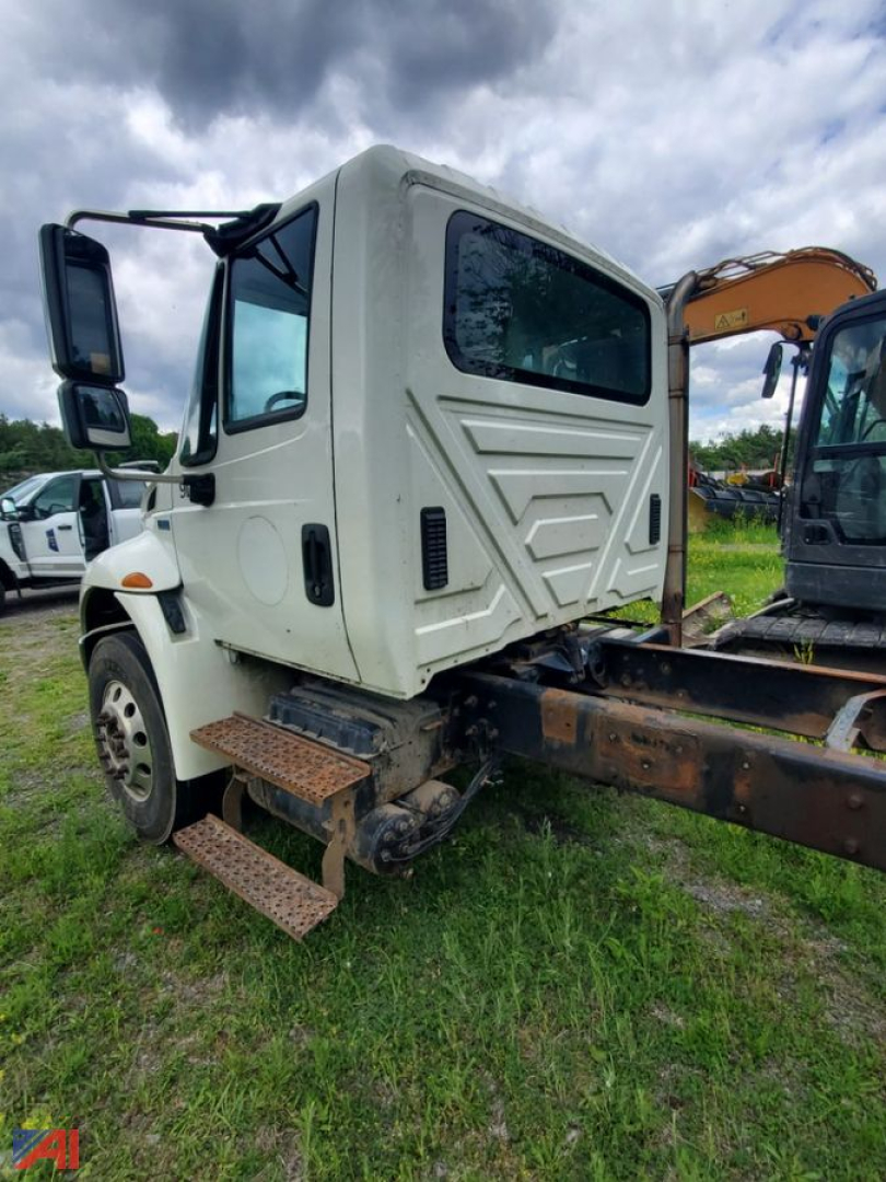 Cab and chassis truck side view showing steps, cab interior visible through window, and chassis frame with mounting brackets.