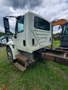 Cab and chassis truck side view showing steps, cab interior visible through window, and chassis frame with mounting brackets.
