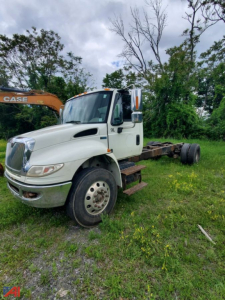 International DuraStar 4400 cab and chassis truck in a field, angled front-left view with no cargo, chassis exposed.