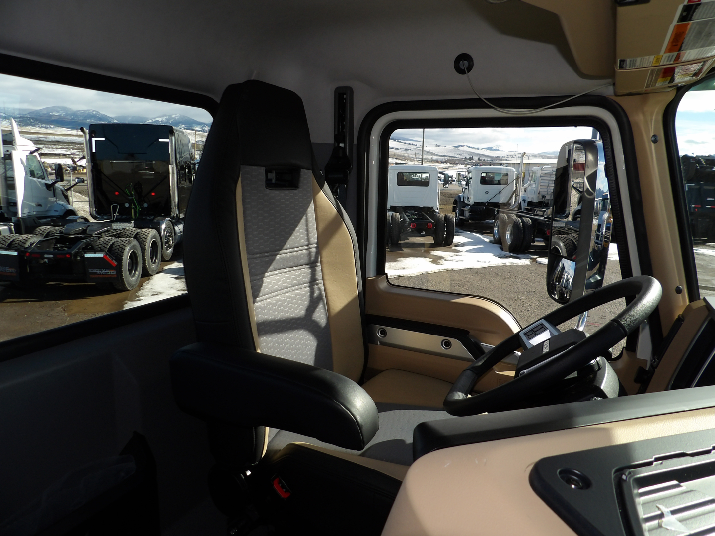 Cab interior of a 2025 Mack GR104F dump truck showing driver's seat, steering wheel, and dashboard with beige trim.