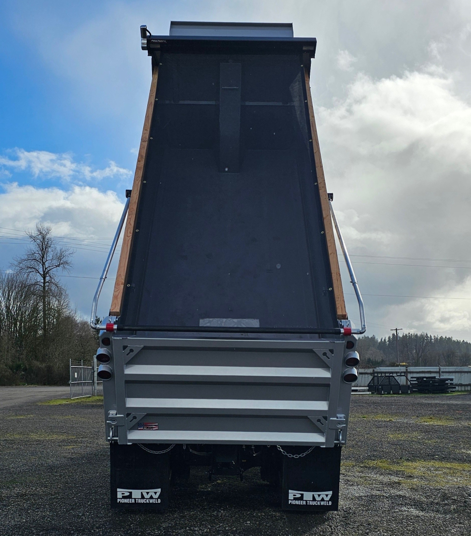 Dump truck bed of a 2025 Mack GR104F showing the open tailgate and hydraulic lift area with gray rear end and side rails.
