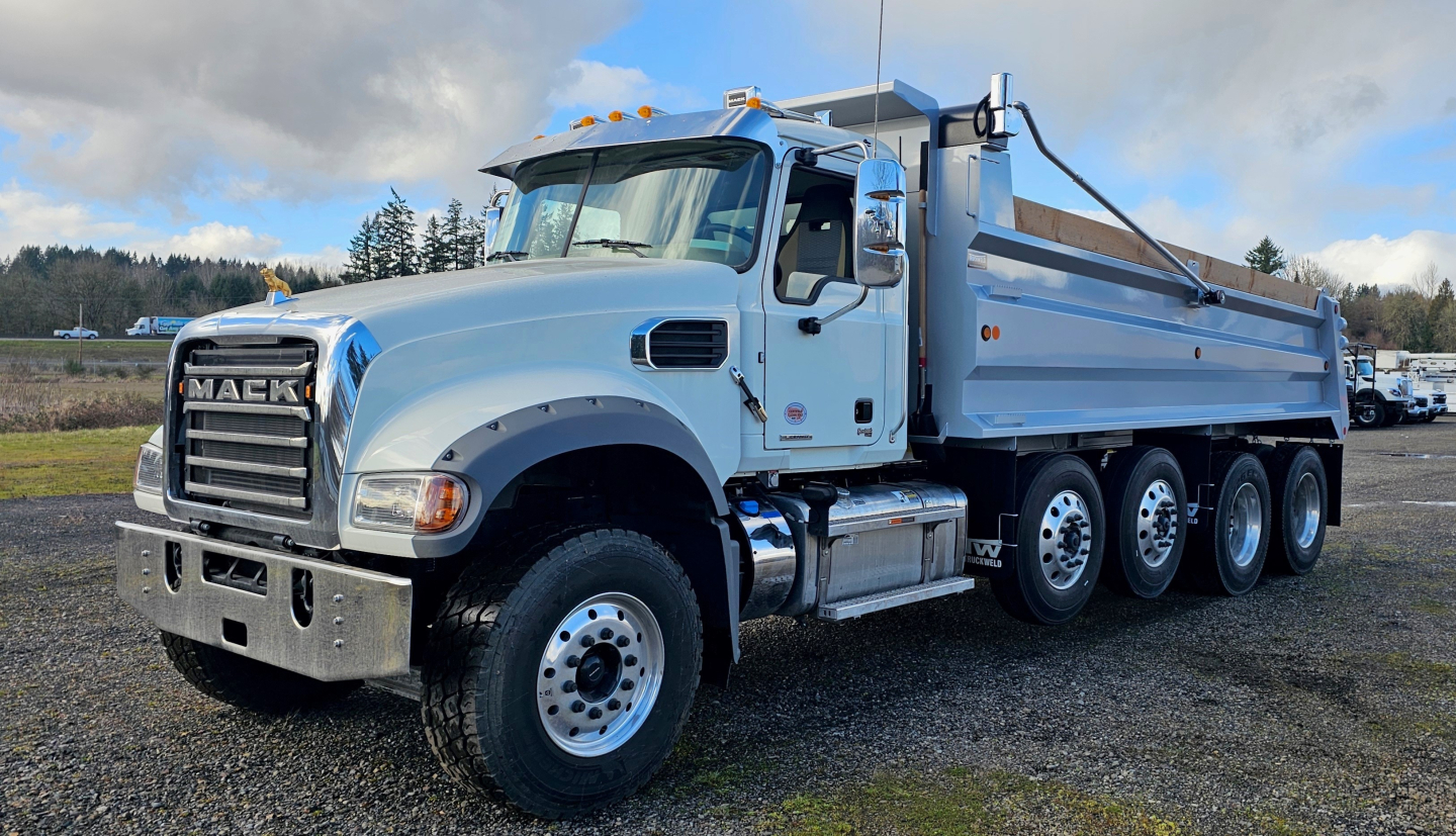 Mack GR104F dump truck showing front grille, cab, and dump bed with multiple axles.