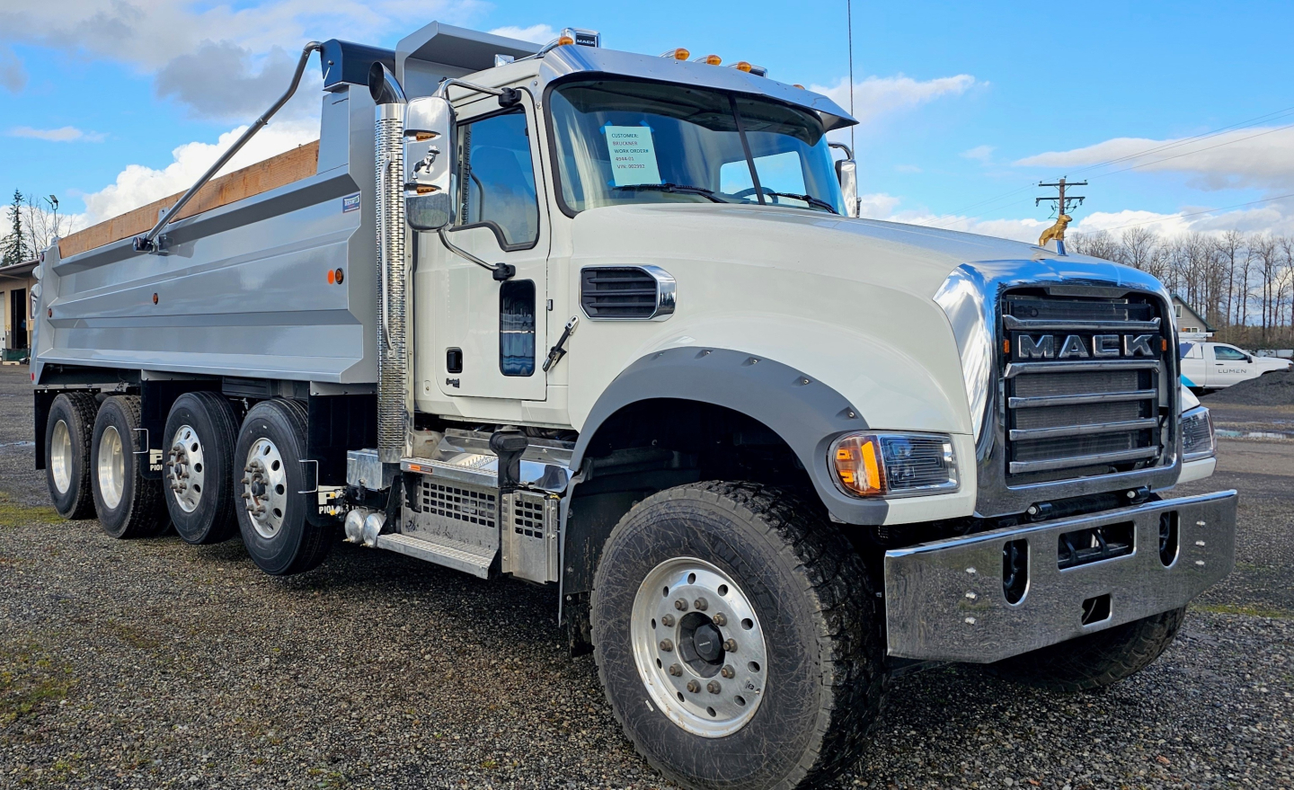Dump truck showing Mack GR104F front grille and multiple axles, light gray cab, white dump bed, stock number 68645 visible.