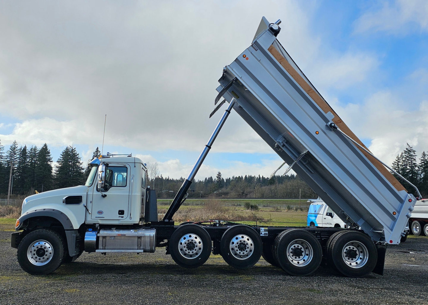 Mack GR104F dump truck side view showing hydraulic dump bed raised on a multi-axle rear trailer