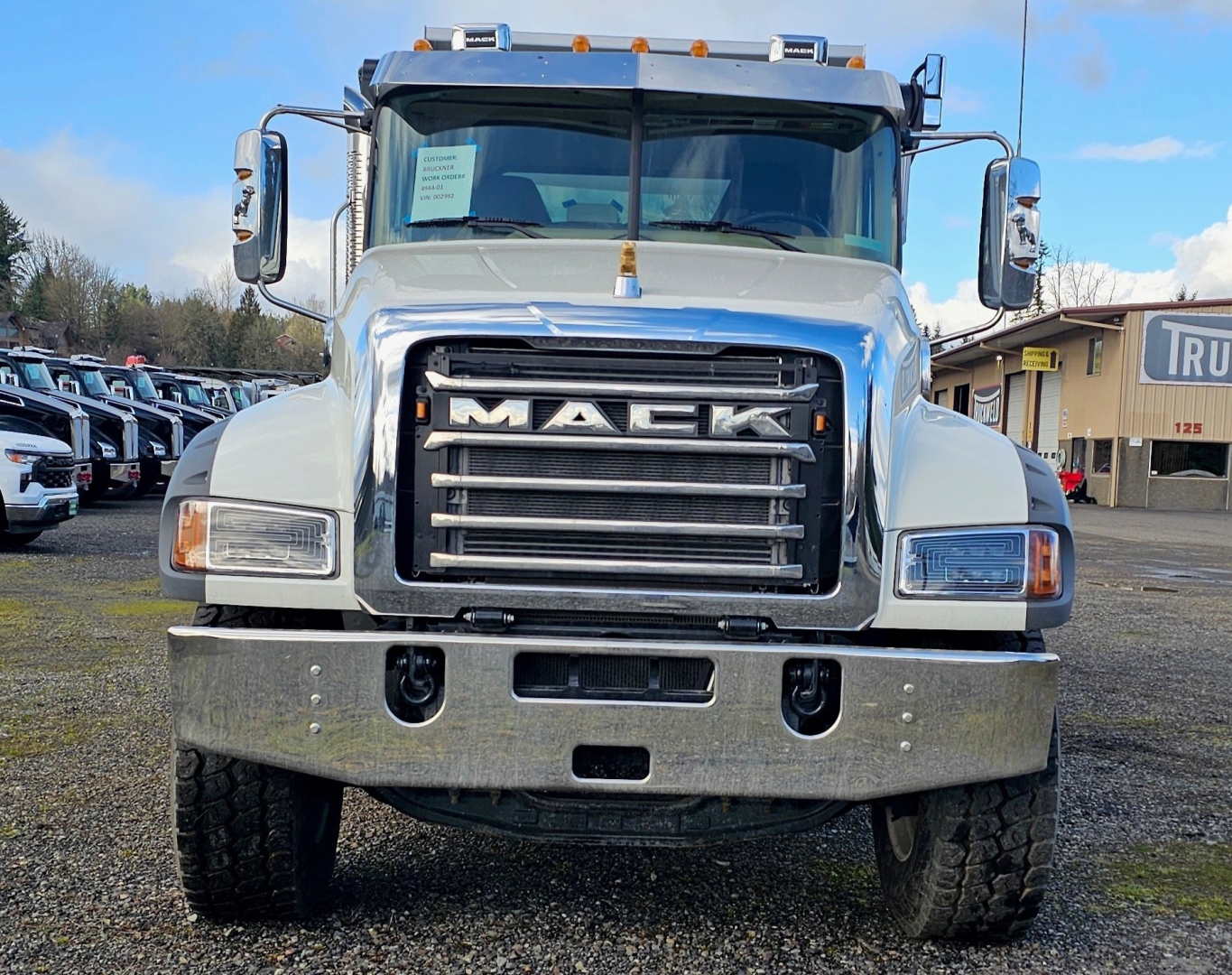 Front view of a 2025 Mack GR104F dump truck showing large chrome grille with MACK lettering, dual headlights, chrome bumper, and side mirrors.