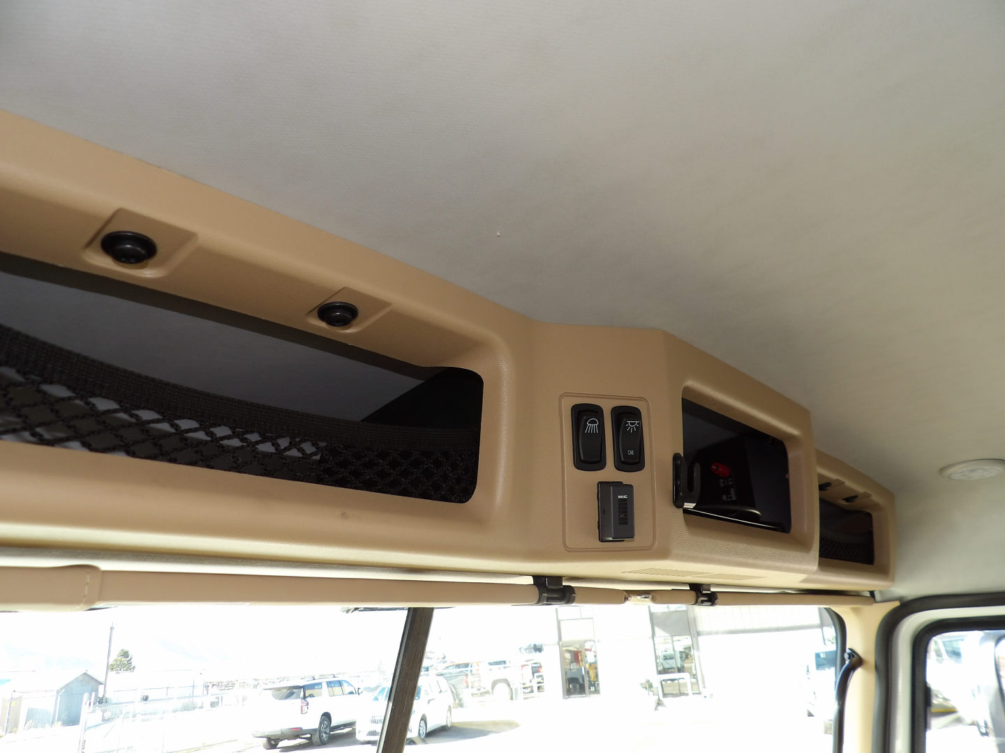 CAB interior overhead controls and storage area with switches and vents, near windshield.