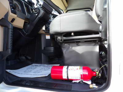 Cab interior of a 2025 Mack GR104F dump truck showing a red fire extinguisher on the floor near the driver seat and dashboard components.