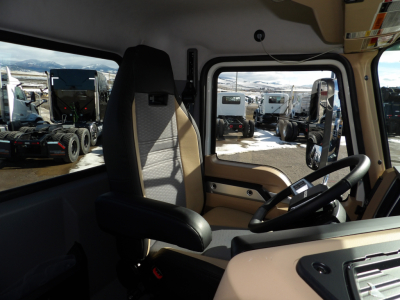 Cab interior of a 2025 Mack GR104F dump truck showing driver's seat, steering wheel, and dashboard with beige trim.