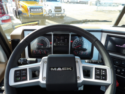 Mack GR104F truck cockpit with steering wheel and instrument cluster; dashboard displays gauges and a central digital screen.
