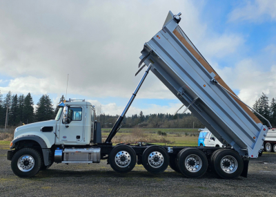 Mack GR104F dump truck side view showing hydraulic dump bed raised on a multi-axle rear trailer