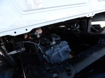 Engine bay showing diesel engine and transmission in a Mack GR104F dump truck, with wiring and hoses visible.