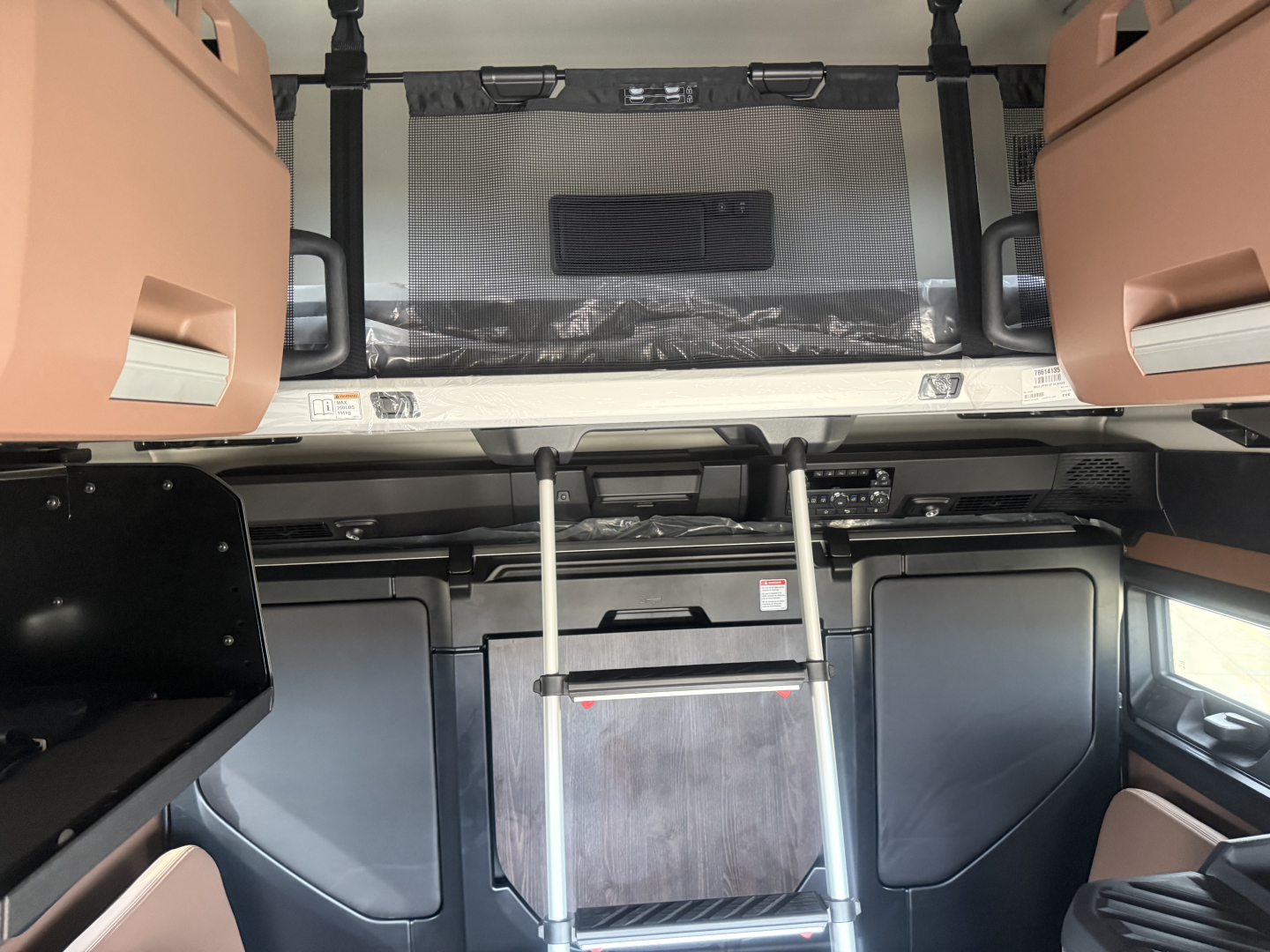 Cab interior of a 2026 Mack PR64T76H sleeper truck showing bunk area, ladder, and storage cabinets.