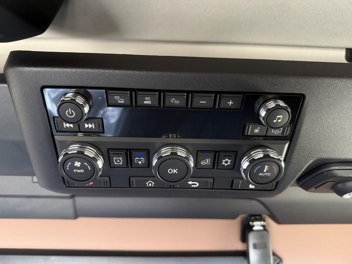 Dashboard control panel of a 2026 Mack PR64T76H showing climate and audio controls, multiple buttons, knobs, and an OK button center.