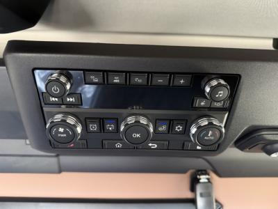 Dashboard control panel of a 2026 Mack PR64T76H showing climate and audio controls, multiple buttons, knobs, and an OK button center.