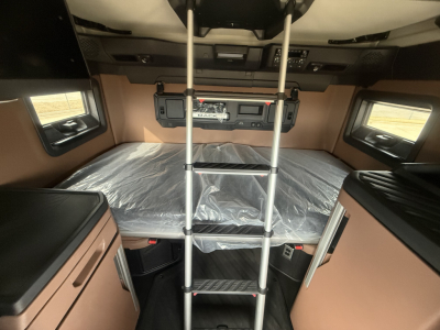 Mack PR64T76H sleeper cab interior showing bunk bed with ladder, storage cabinets, and plastic-covered mattress.