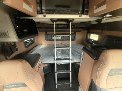 Mack PR64T76H sleeper cab interior showing bunk bed area with ladder and tan leather seats.