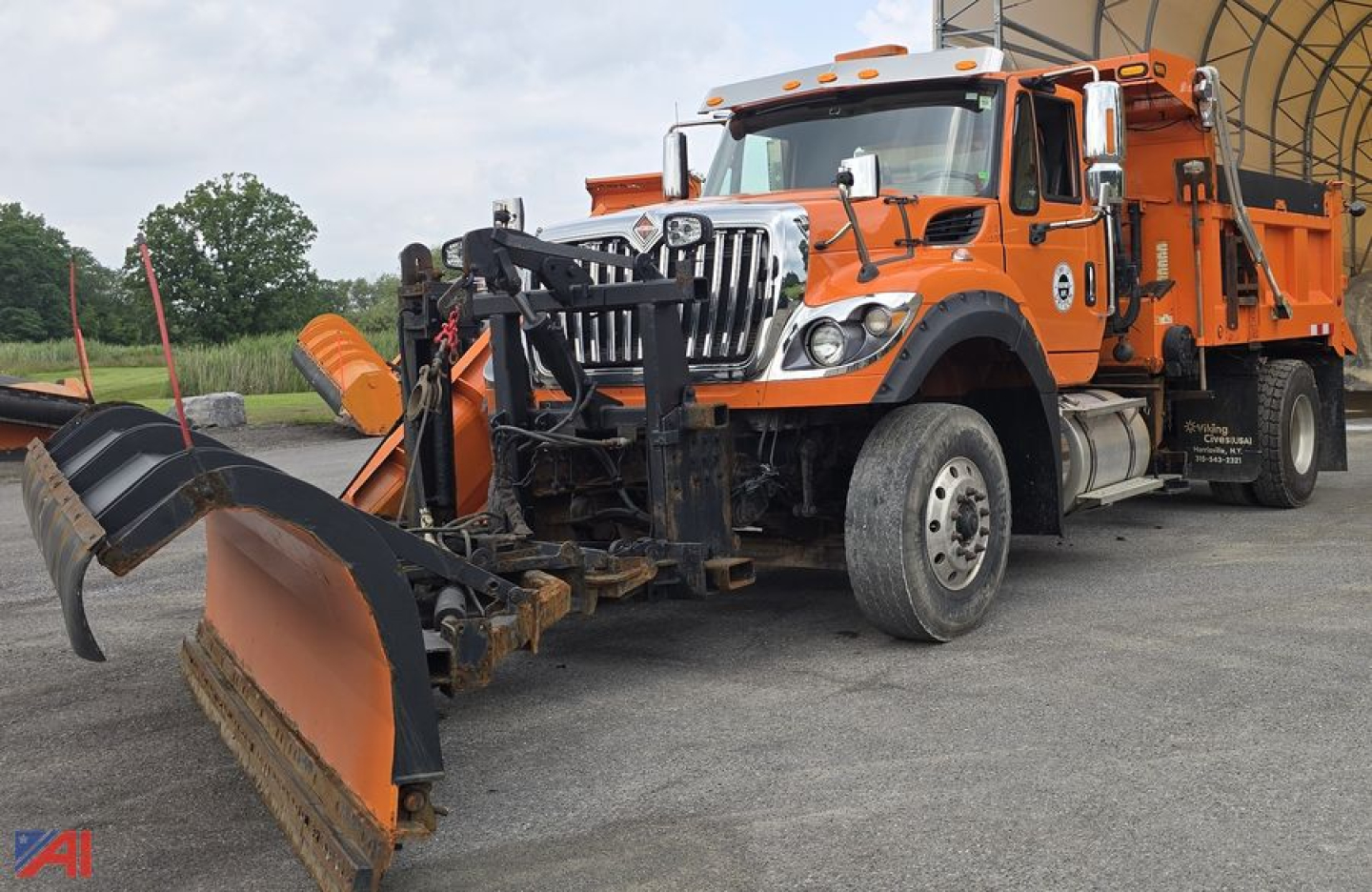 Dump truck with plow attachment in front, orange International 7600 SFA, side view showing snowplow equipment and front blade.