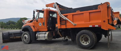 Dump truck with plow and hopper shown side view. 2018 International 7600 SFA dump truck in orange with plow attachment and side-mounted fuel tanks.
