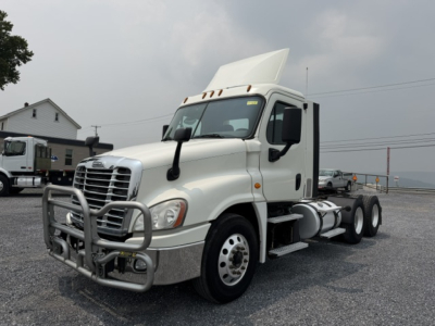 Truck cab and trailer chassis of a white 2017 Freightliner Cascadia CA125DC with a raised hood and front bumper guard.