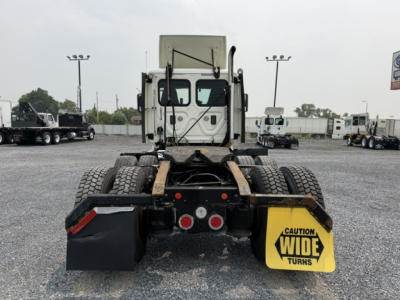 Rear view of 2017 Freightliner Cascadia CA125DC tractor chassis showing dual rear axles, mud flaps, and ‘Caution Wide Turns’ sign.