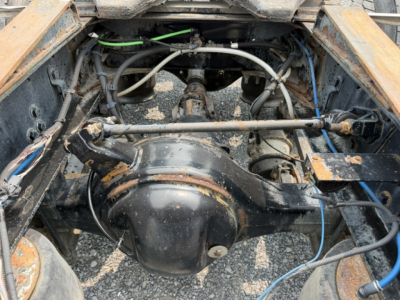 Freightliner Cascadia drivetrain view in a daycab showing rear axle differential, suspension components, and various hoses and wiring.