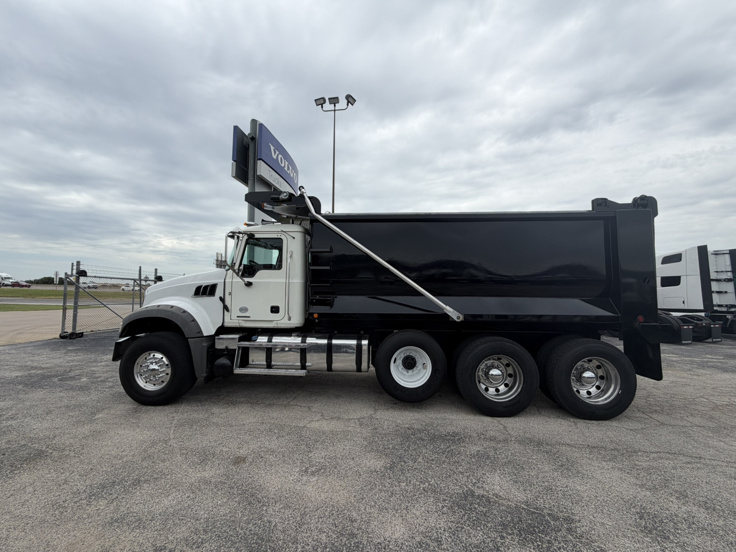 2021 Mack GR64F dump truck side view showing VIN plate in the cab area and multiple axles with a black dump body.